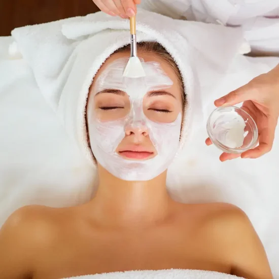 Esthetician applying facial mask with brush during spa treatment